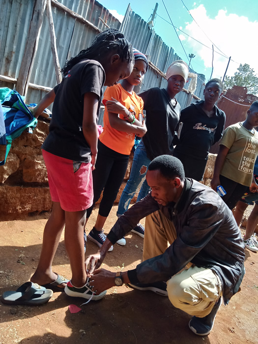 Sammy helping by donating shoes to Children in Kibera Slum
